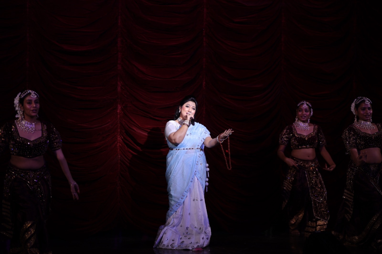 A vocalist performing live on stage with the company's dancers
